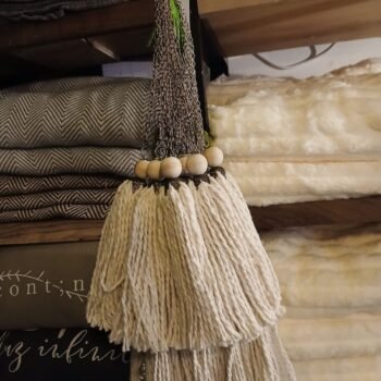 Borla sujeta cortina de hilos color crudo con dije de madera y cadena de bronce