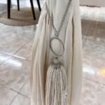 Borla sujeta cortina de hilos color crudo con dije colgante de cristal y plata